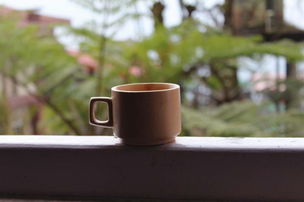 coffee cup mug on white surface near leaves pottery